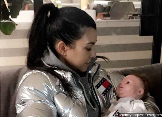 Kourtney Kardashian Cradles Baby Doll While Covering Her Belly in New Pic